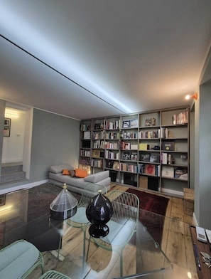 Una sala de estar moderna con un sofá, una mesa de centro de vidrio y una estantería llena de libros.