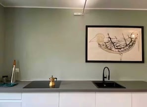 A kitchen with a black sink, a framed artwork on the wall, and a small pot on the counter. - 09 - Loft Library - Studio Apartment, Sleeps 2 (Oggebbio)