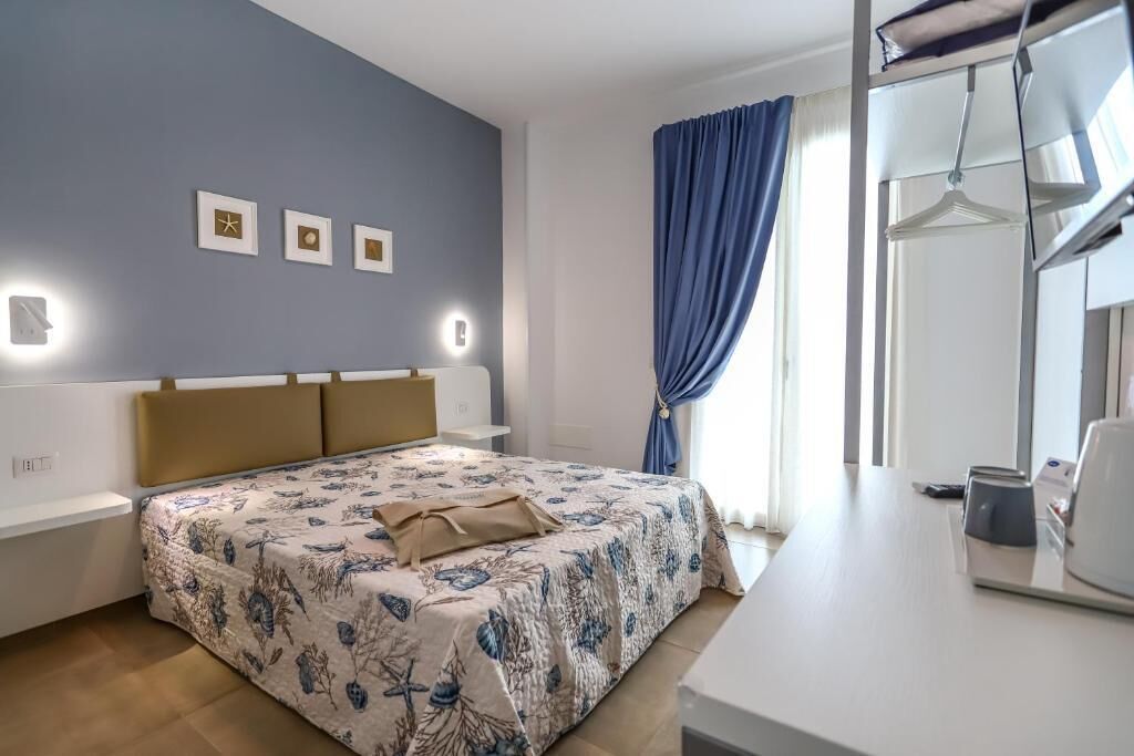 Ein Schlafzimmer mit einem Bett, Nachttischen, einem Spiegel und einem Fenster mit Vorhängen.