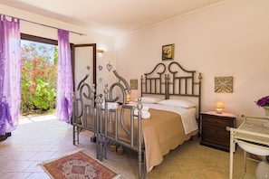 A bedroom with a bed, a nightstand, a dresser, a window with curtains, and a view of greenery outside. - Uva Regina by Casa di Marco (Gallipoli)
