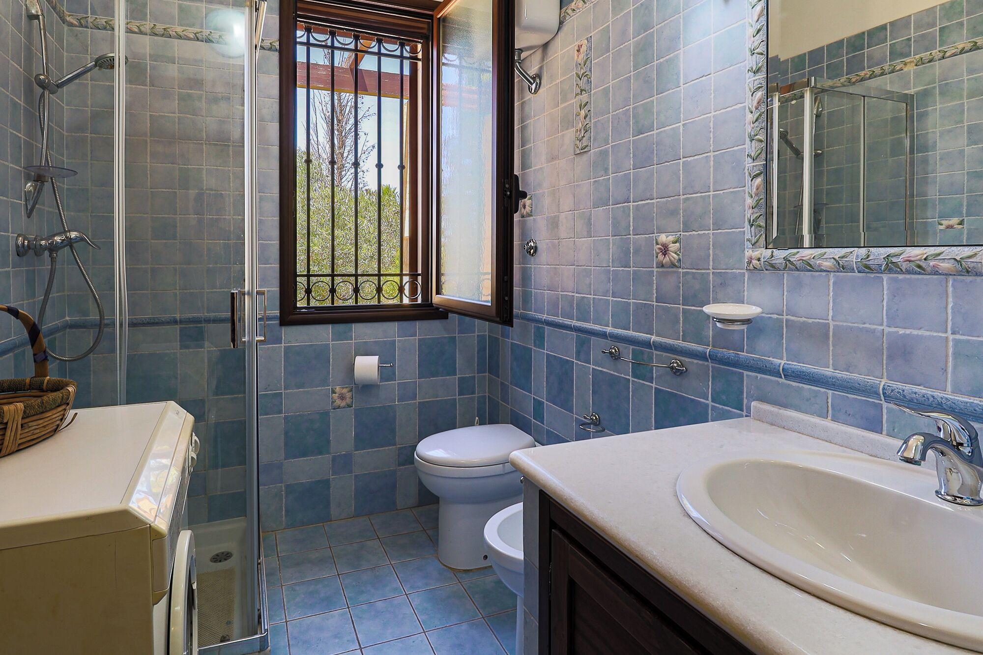 Un bagno con doccia, toilette, lavandino e una finestra vista.