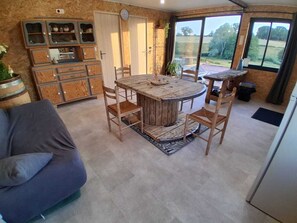 Un salon chaleureux avec une table ronde en bois, un canapé et un meuble encastré en bois doté de portes en verre.