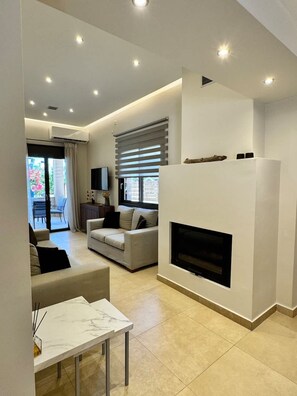A modern living room with a fireplace, a sofa, a TV, and a dining area with a marble table.