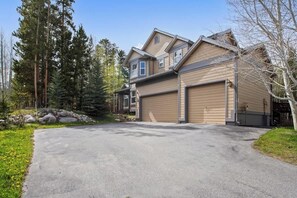 A two-story house with a garage, surrounded by trees and a driveway.