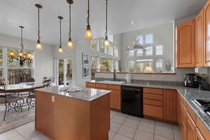 Eine moderne Küche mit Granit Arbeitsplatten, Holzschränken und Pendelleuchten.