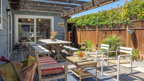 A covered patio with a wooden pergola, outdoor furniture, and potted plants. - The Point House steps to Pleasure Point! (Santa Cruz)
