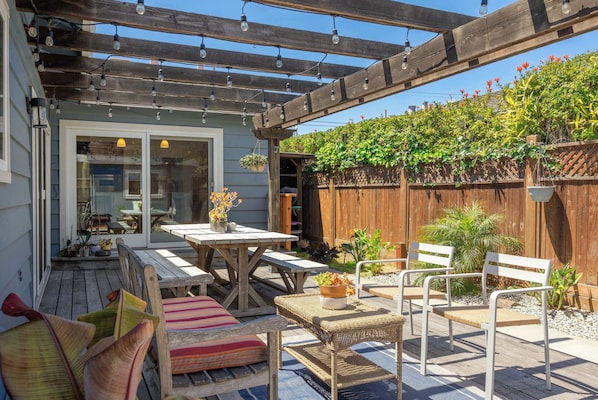 Eine überdachte Terrasse mit einer Holz-Pergola, Gartenmöbeln und Topfpflanzen.