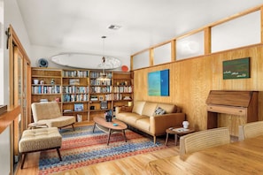 Ein gemütliches Wohnzimmer mit einer Couch, Sesseln, einem Couchtisch, einem Bücherregal und einem Holzschrank.