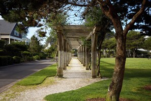 A pathway lined with trees and a pergola structure.