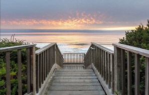 Une promenade en bois menant à une plage d’où l’on peut admirer le coucher du soleil.