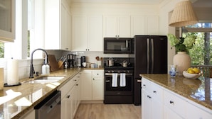 A modern kitchen with white cabinetry, a black microwave, a black refrigerator, and a granite countertop. - Beach Walk, Hot Tub, Pool, Gym, Fire Pit, Games, Sleeps 13 (Lincoln City)