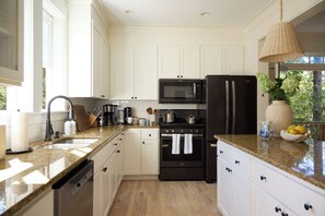 Eine moderne Küche mit weißen Schränken, einer schwarzen Mikrowelle, einem schwarzen Kühlschrank und einer Arbeitsplatte aus Granit.