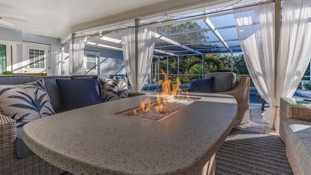Un área de estar al aire libre con techo, una chimenea, muebles de mimbre y vistas al exterior.