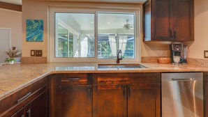 Una cocina con un amplio ventanal, electrodomésticos de acero inoxidable y armarios de madera.