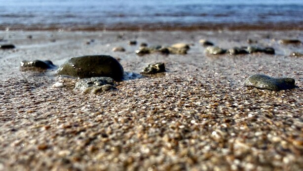 Een strand met kiezels en losse rotsen.