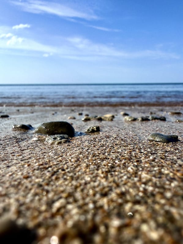 Ein Strand mit Kieselsteinen und verstreuten Felsen.