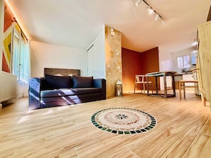 Ein modernes Wohnzimmer mit einer Couch, einem Esstisch und einem gemusterten Boden.