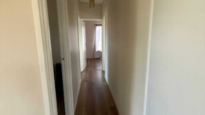 A narrow hallway with wooden flooring and white walls. - Prom Coast Residence (Fish Creek)