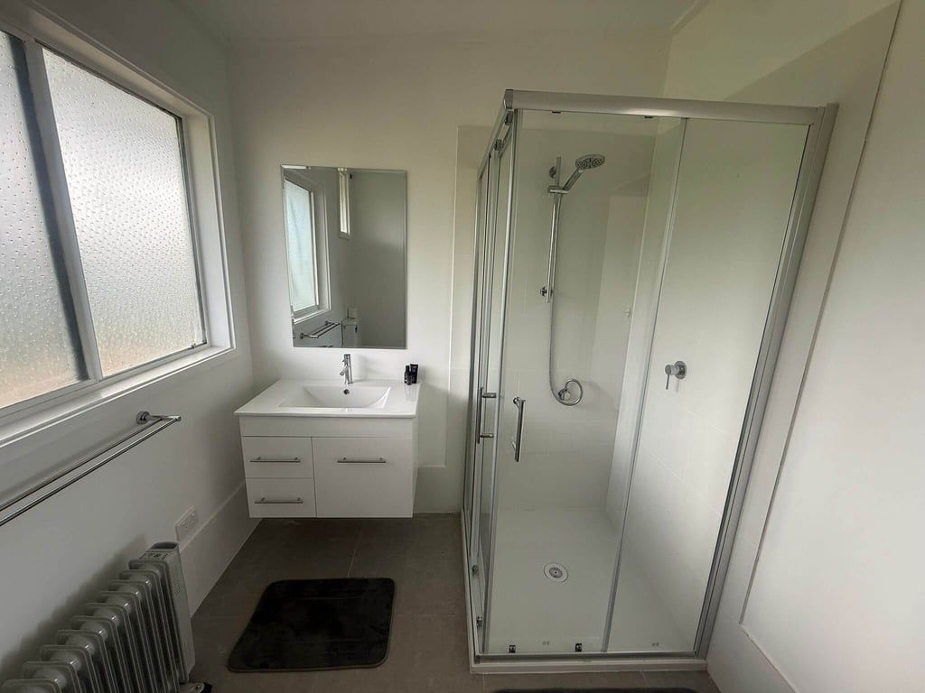 A bathroom with a glass-enclosed shower, a white sink, and a mirror above it.