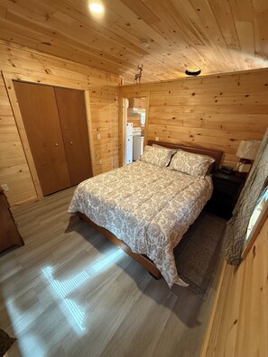 A wooden-paneled bedroom with a bed, a nightstand, and a wardrobe.