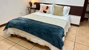 Un dormitorio con una cama, una mesita de noche con lámpara y dos obras de arte en la pared.