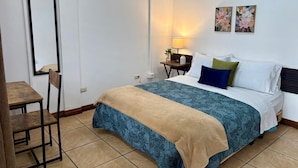 Un dormitorio con cama, mesita de noche, silla y lámpara.
