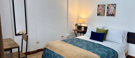 Un dormitorio con cama, mesita de noche, silla y lámpara.