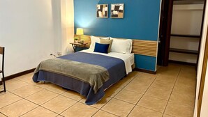 A bedroom with a bed, a nightstand, a lamp, and a wall-mounted artwork.