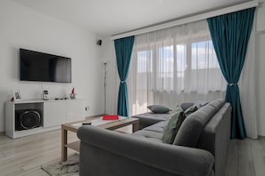 A modern living room with a flat-screen TV, a sofa, a coffee table, and a white entertainment unit.