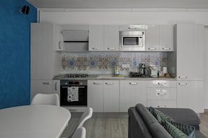 A modern kitchen with white cabinets, a microwave, a stove, and a patterned backsplash.