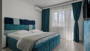 A modern hotel room with a large bed, a nightstand, and a TV. - 2-bedroom apartment in awesome București with AC and comfort (București)