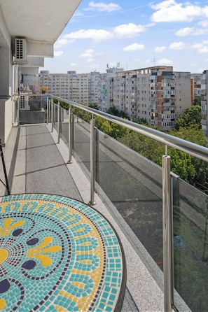 A balcony with a tiled floor, metal railing, and a view of high-rise buildings.