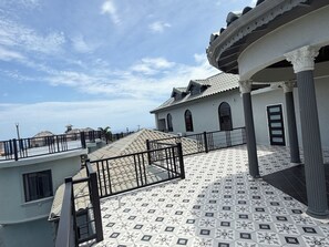 A building with a tiled roof, a balcony with a railing, and a door. - Upscale Caribbean Retreat with Oceanview Balcony & Resort Style Living (Montego Bay)