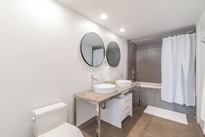 Ein modernes Badezimmer mit Toilette, zwei Waschbecken, einer Dusche und einer Badewanne.