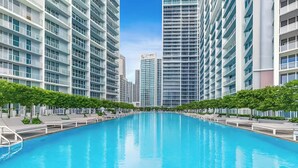 Un hotel moderno con una piscina central, rodeado de edificios altos y vegetación.