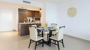 Una cocina moderna con electrodomésticos integrados, un comedor con una mesa redonda y sillas, y un adorno en la pared.