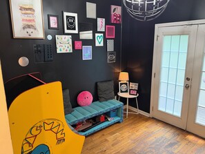 A room with a blue sofa, a yellow chair, a small table with a lamp, and a door with frosted glass panels. - A Spin In Atlanta Westend (Atlanta)
