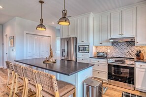 A kitchen with white cabinets, a central island, a stainless steel refrigerator, a microwave, a toaster, and an oven. - Luxury Stay|Free Linens & Baby Items|Walk to Beach|High End Design and Amenities (Surf City)