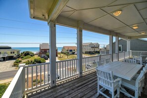 A covered outdoor area with a wooden deck, white railings, and a table with chairs. - Luxury Stay|Free Linens & Baby Items|Walk to Beach|High End Design and Amenities (Surf City)