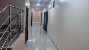 Un pasillo con una escalera de metal a la izquierda, puertas a la derecha y suelo de baldosas.