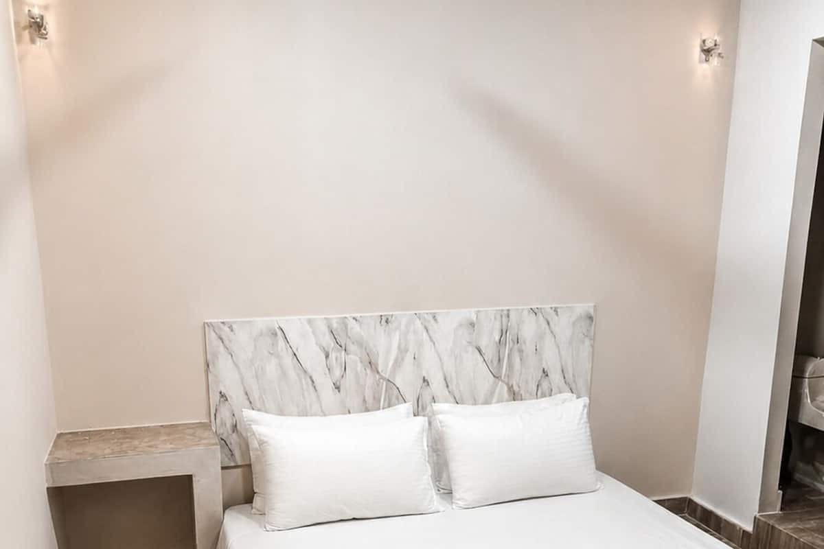 A bedroom with a marble headboard, a bed with white bedding, a nightstand, and a ceiling fan.