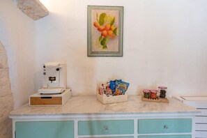 Eine Küche mit einer Kaffeemaschine, einem Obstkorb und Gläsern auf der Arbeitsfläche.