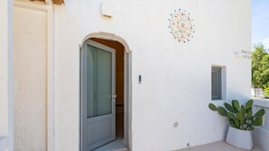 Ein weißes Gebäude mit einer Tür, einem kleinen Fenster und einem Blumentopf.