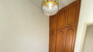A bedroom with a bed, wooden wardrobe, and a decorative ceiling light. - Sugarloaf - Rio Sul 2 bedroom apartment (Rio de Janeiro)