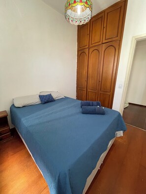 Ein Schlafzimmer mit einem Bett, einem Holzschrank und einer dekorativen Deckenleuchte.
