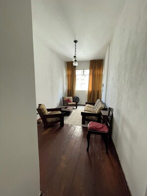 Ein Zimmer mit Holzboden, zwei Sofas, einem kleinen Tisch und einem Deckenventilator.