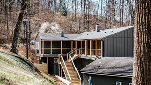 A two-story building with a staircase leading to a deck, surrounded by trees. - Double Queen Room near Blue Ridge Tunnel (Waynesboro)