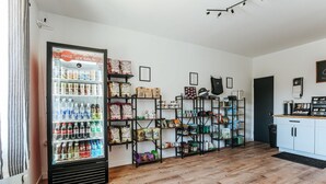 A room with a refrigerator stocked with beverages, shelves with snacks and books, and a coffee machine. - Double Queen Room near Blue Ridge Tunnel (Waynesboro)