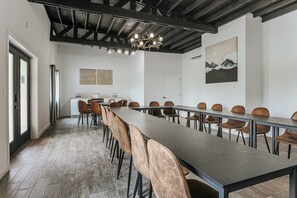 Uma sala de conferências com uma longa mesa, cadeiras, um candelabro e obras de arte nas paredes.