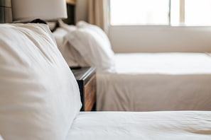 Una habitación de hotel con una cama, una mesita de noche y una lámpara.